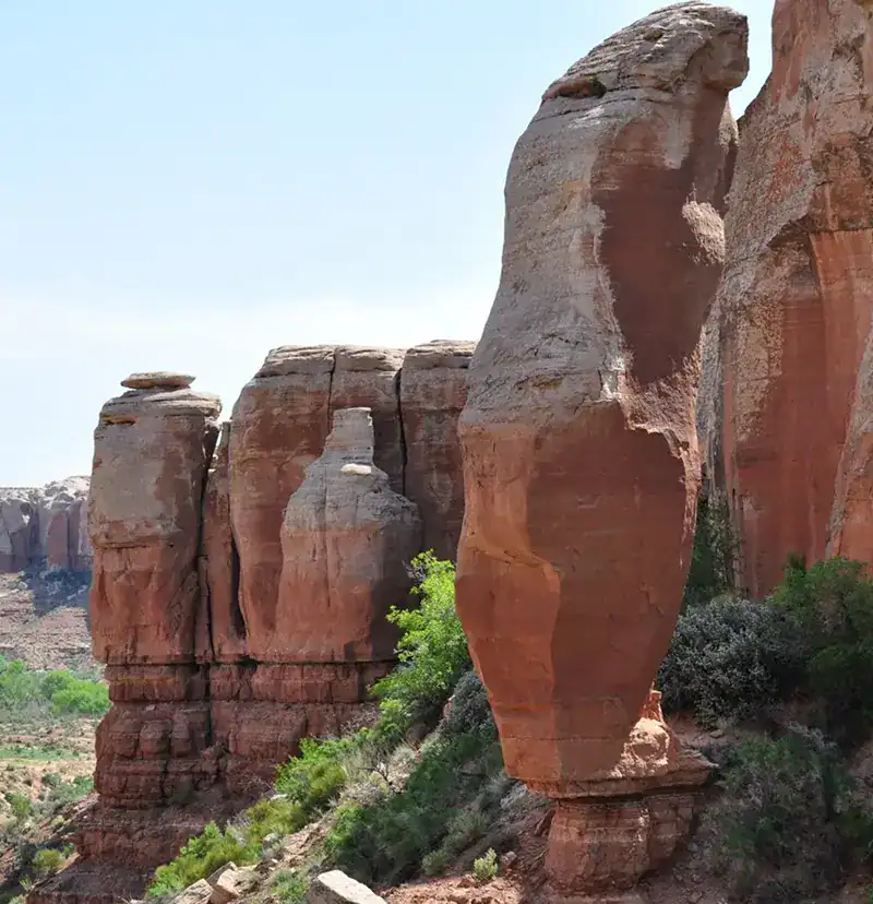 Unique red rock formations in a desert landscape with green vegetation.