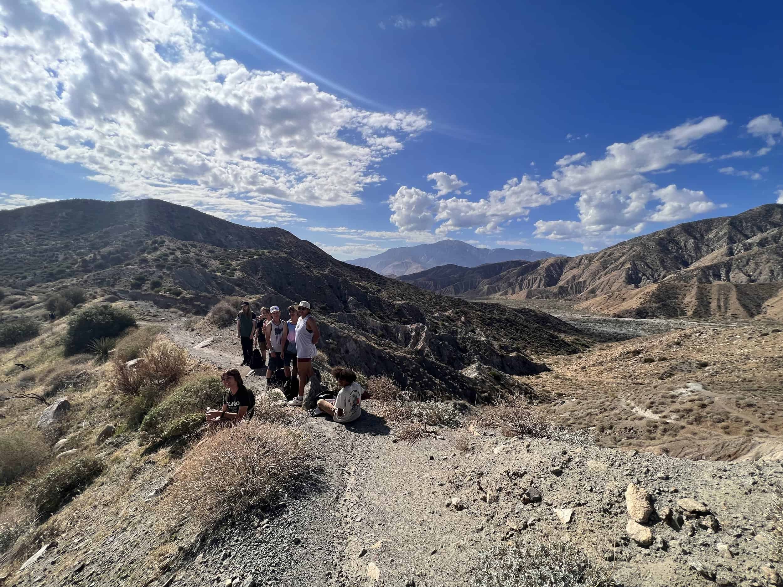 Group of hikers exploring a rugged desert canyon landscape.