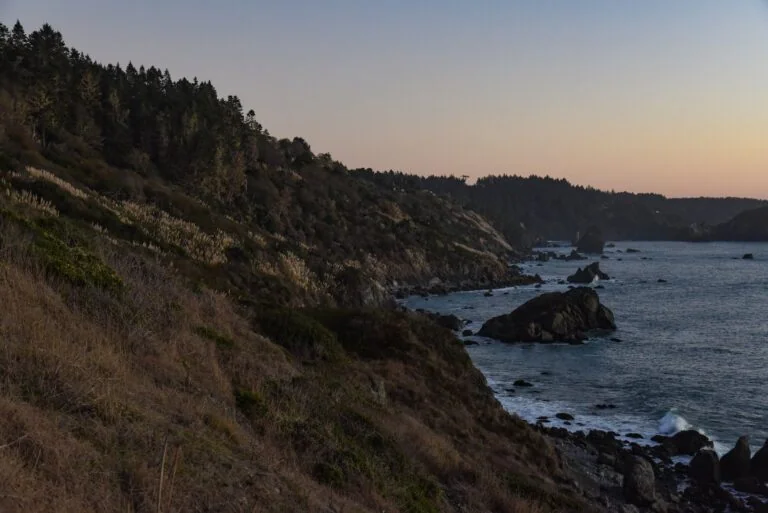Scenic coastal landscape with cliffs and ocean at sunset.