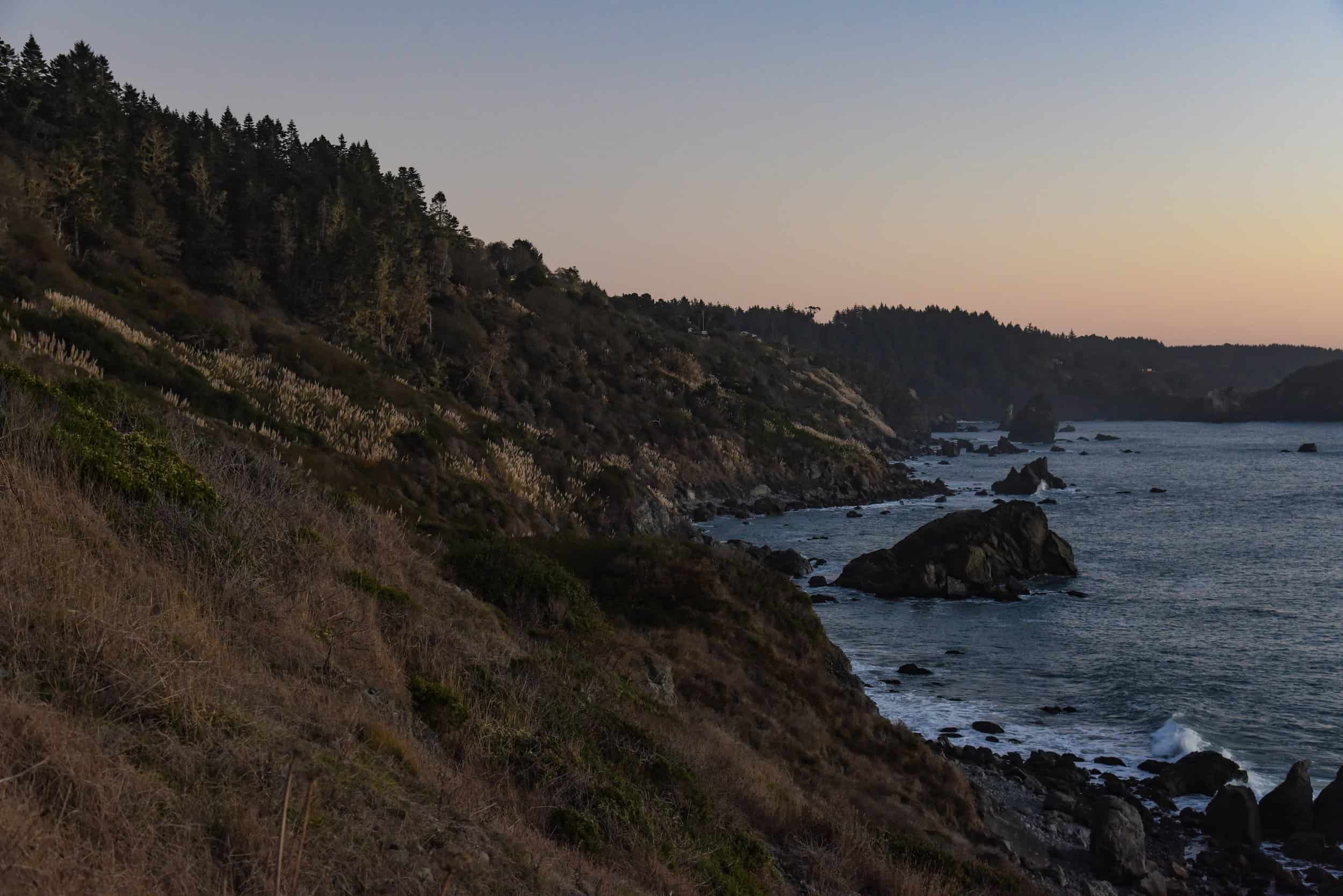 Scenic coastal landscape with cliffs and ocean at sunset.