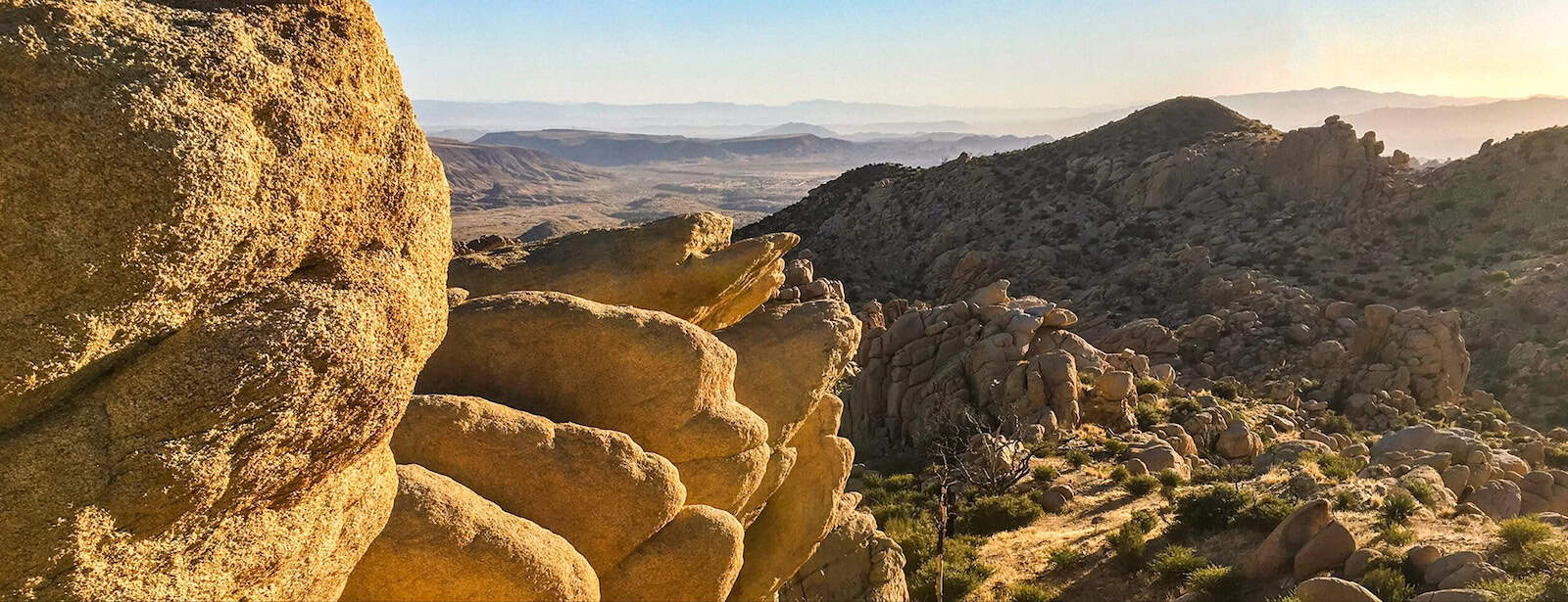 Breathtaking desert landscape with rocky hills and distant mountains at sunset.
