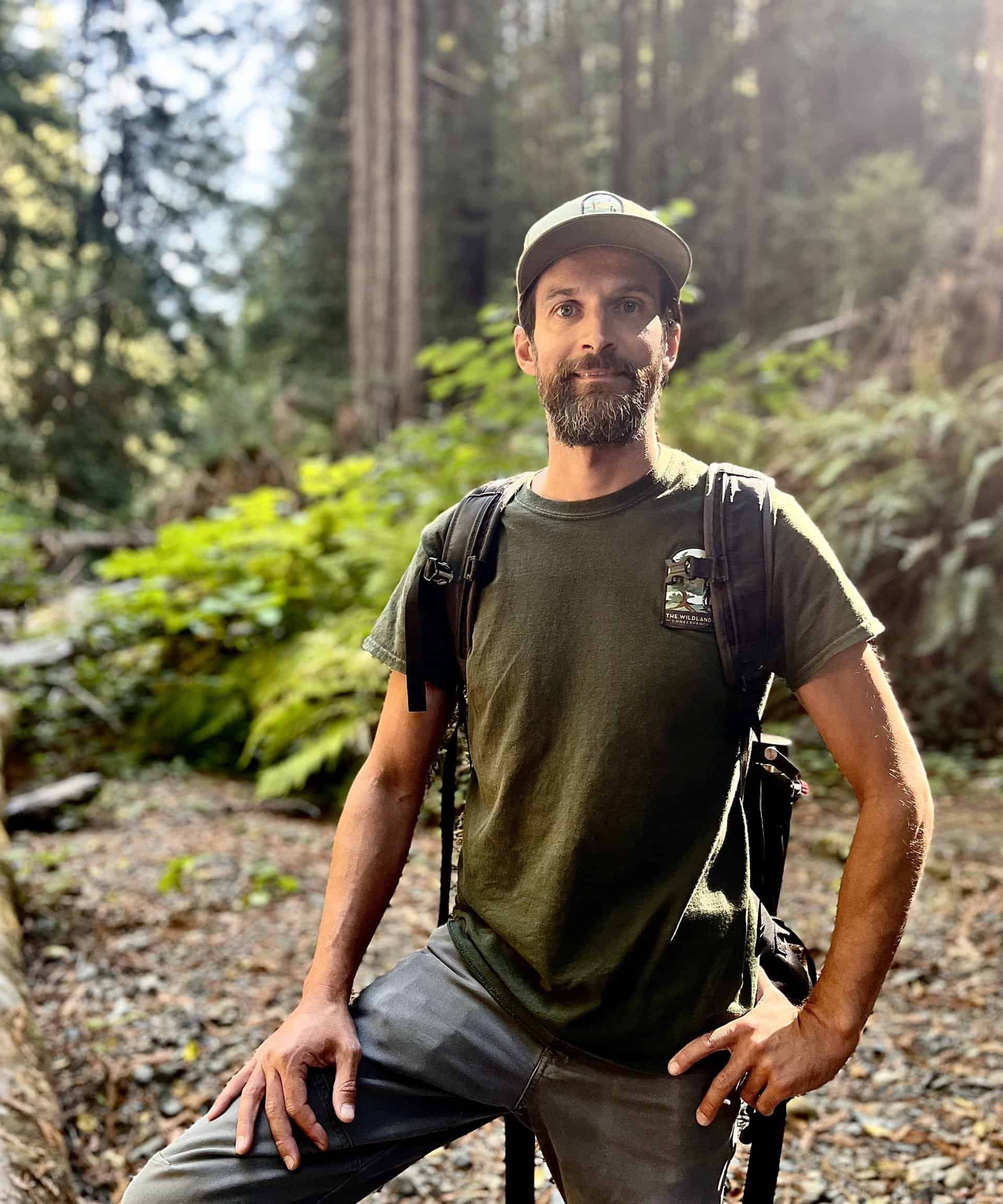 Man hiking in lush forest with backpack at The Wildlands Conservancy.