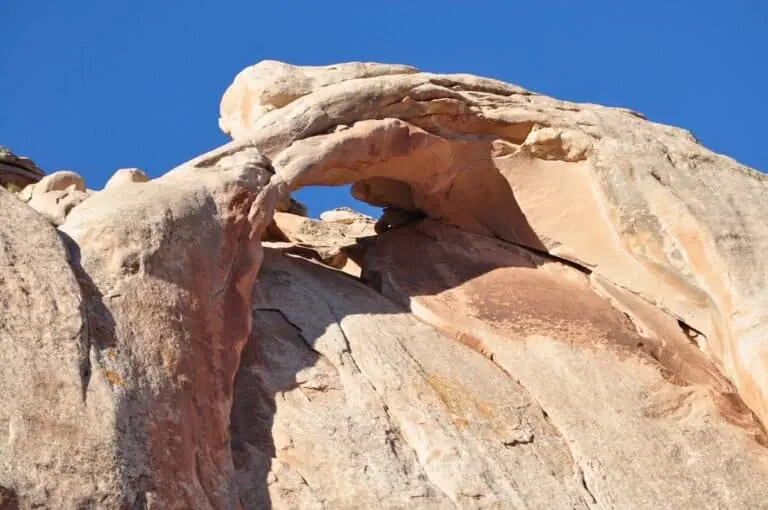 Natural rock arch formation under a clear blue sky.