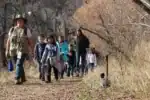 Group of children and adults on nature walk in a forested area.