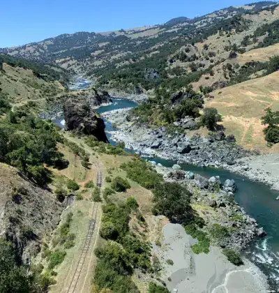 Beautiful river flowing through lush green valley with mountains in the background.