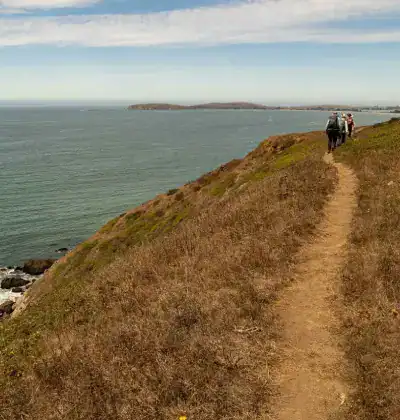 Hikers walking along a coastal trail overlooking the ocean.