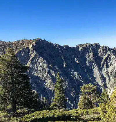 Majestic mountain range with lush greenery and clear blue sky.