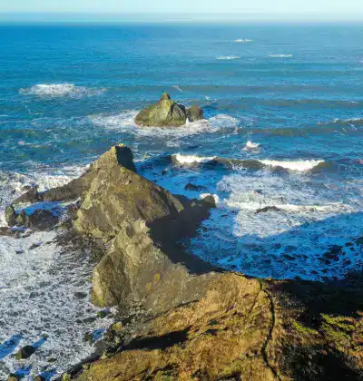 Scenic coastal rocks with ocean waves crashing against them.