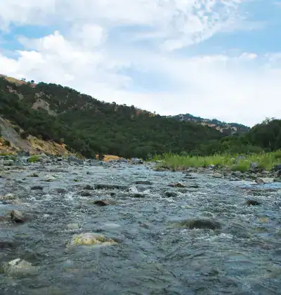 River flowing through scenic landscape with hills and trees.