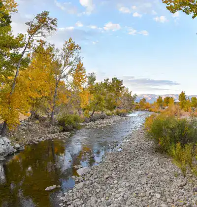 River flowing through autumn landscape with colorful trees and rocky banks.