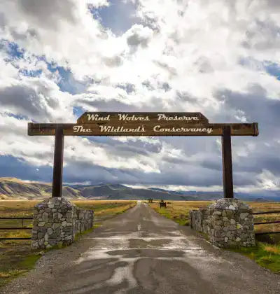 Entrance sign for The Wildlands Conservancy with scenic landscape background.