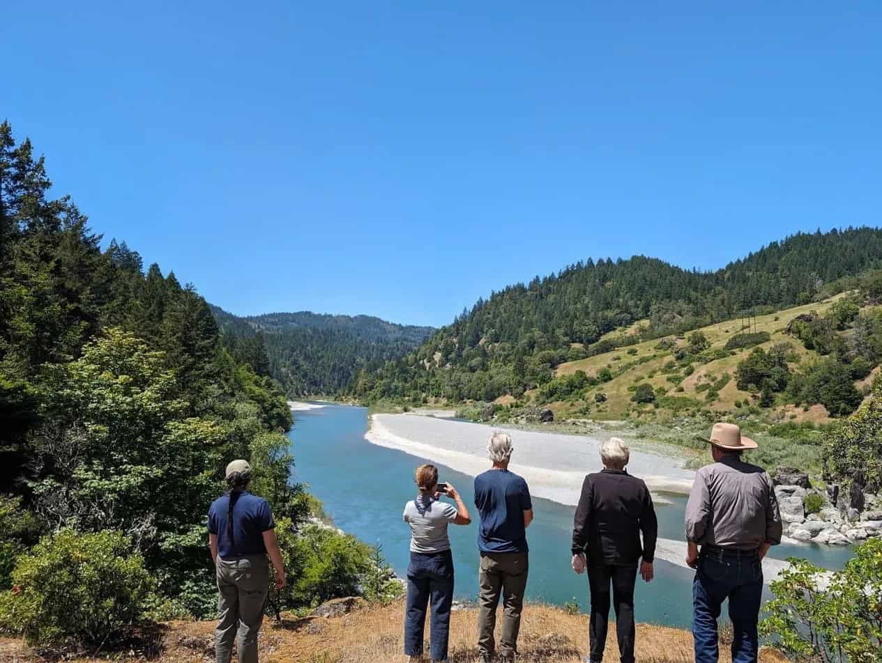 Group of people enjoying scenic view of river and mountains at Eel Rock Ranch.