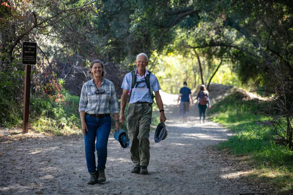 Hikers walking on a trail surrounded by lush trees at The Wildlands Conservancy.