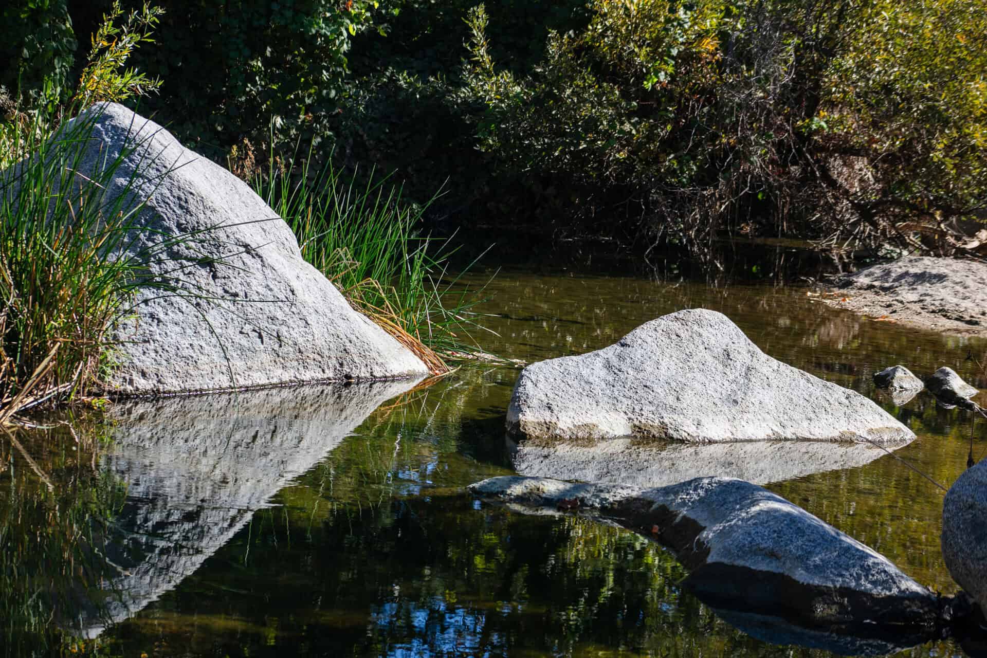 Tranquil river scene with large rocks and calm water at Wildlands Conservancy.