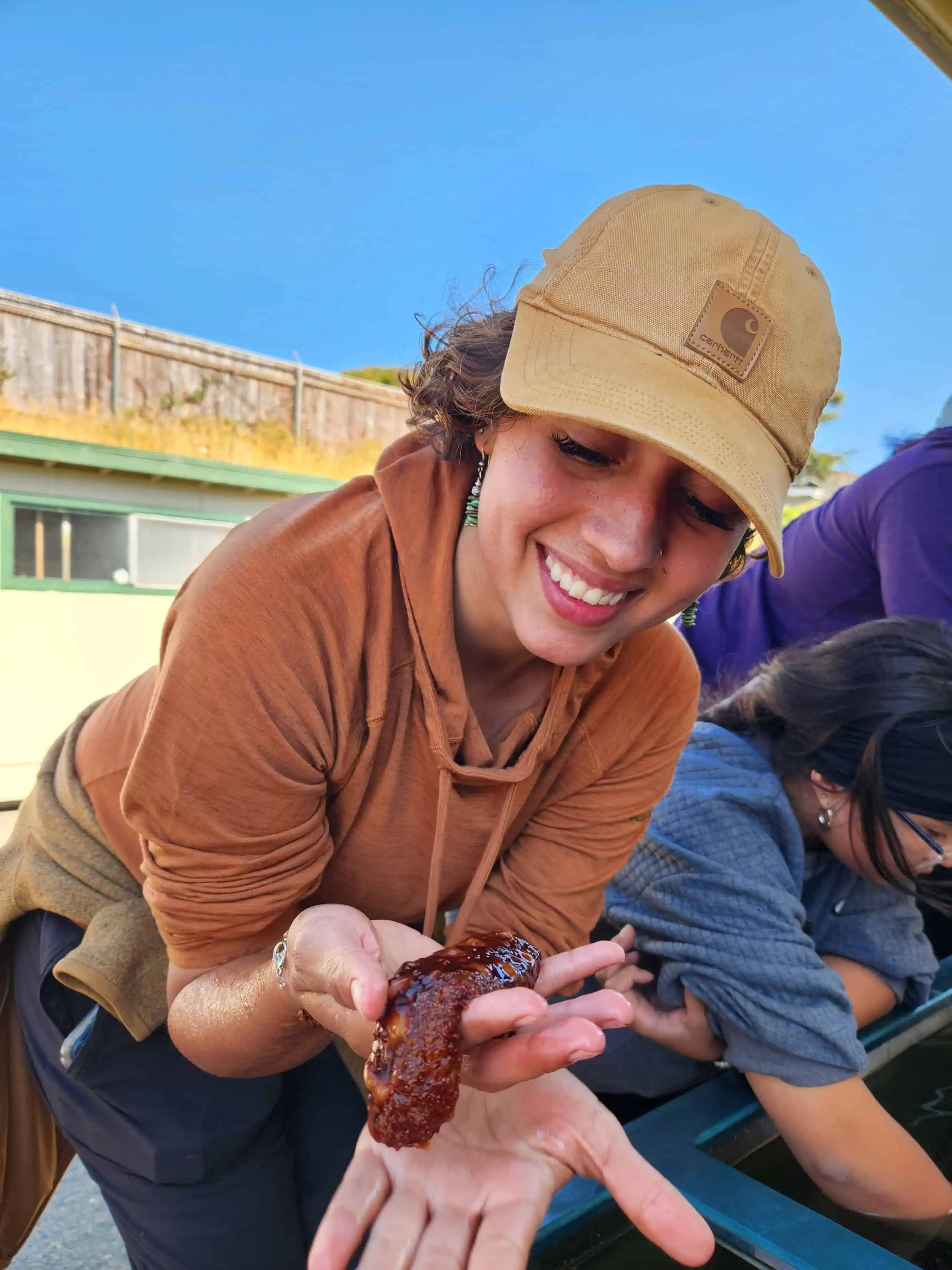 Woman holding a small animal in a natural outdoor setting.