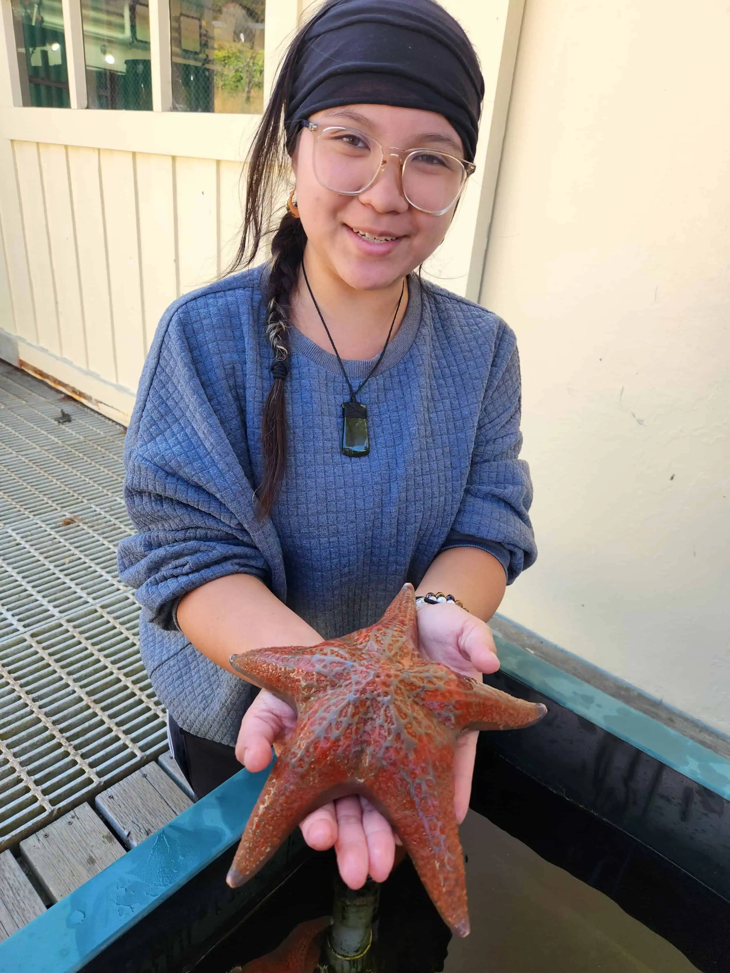 Young woman holding a large starfish at Wildlands Conservancy.