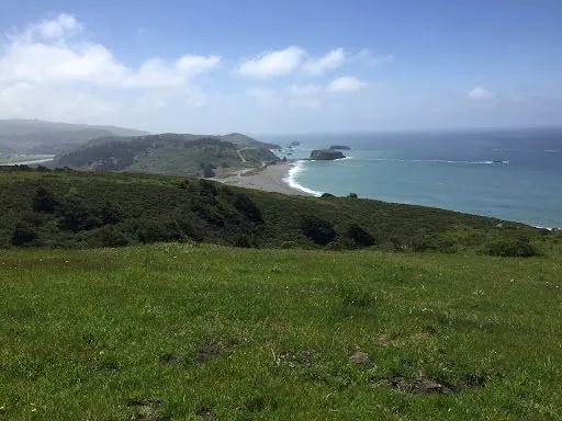 Beautiful coastal landscape with green hills and ocean waves.