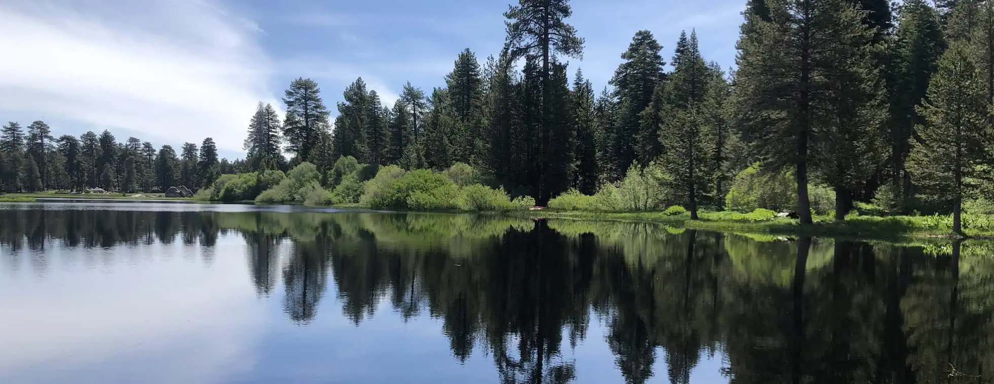 Wildlands Conservancy lake with calm water and lush forest backdrop.