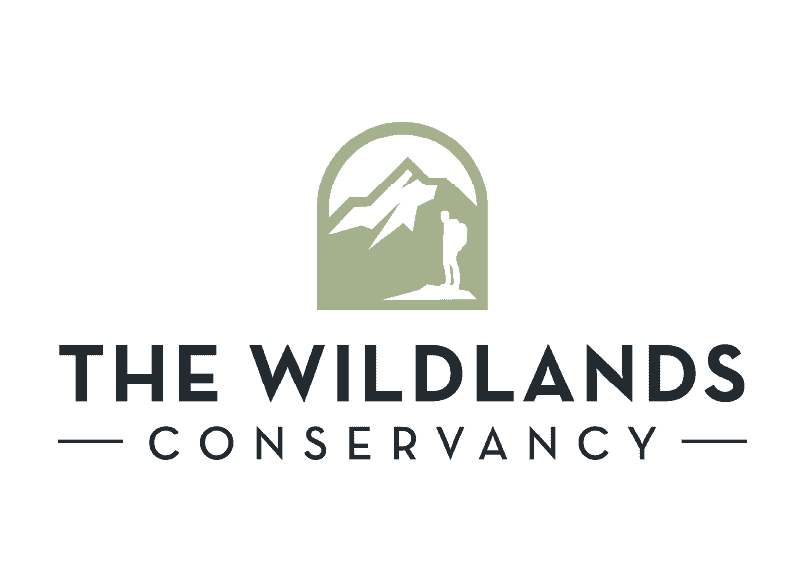A lush green landscape with mountains and a river, representing The Wildlands Conservancy's natural.