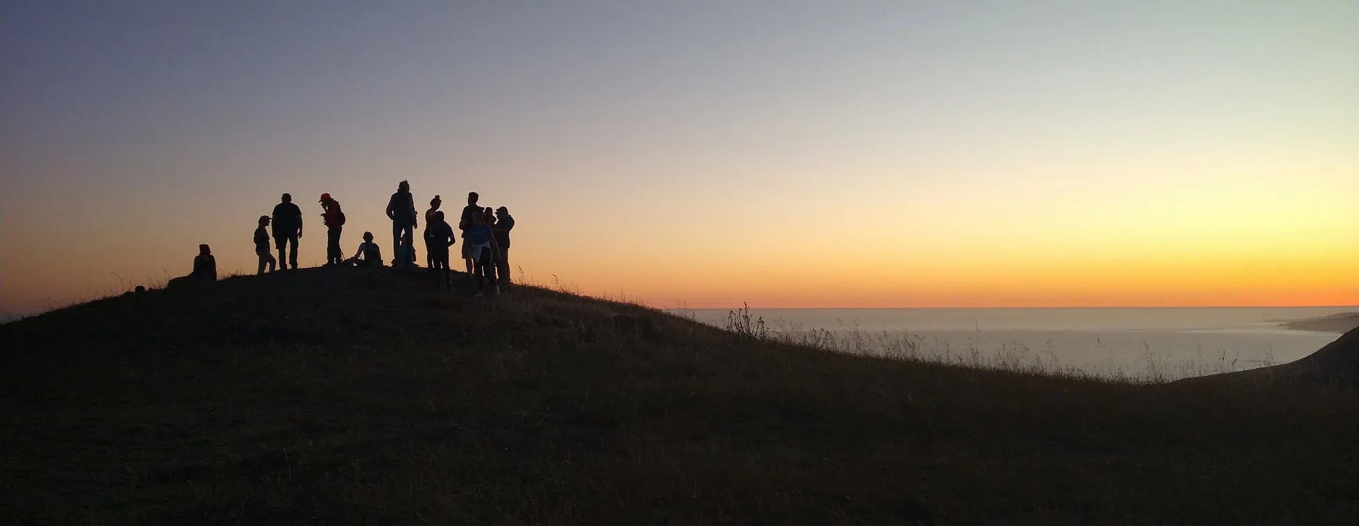 Group of people watching sunset from hilltop at Wildlands Conservancy.